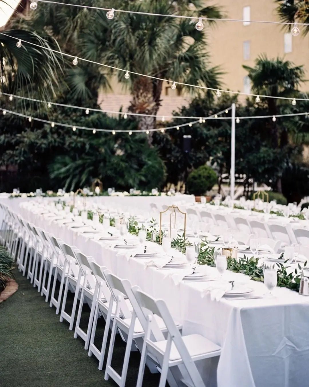 Klappstuhl Weiß an einer langen Hochzeitstafel im freien